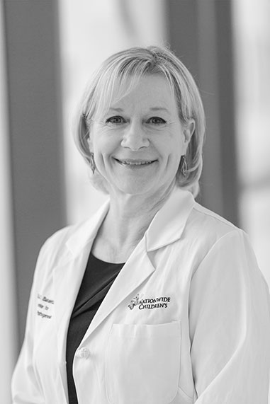 Black and white environmental portrait of Dr. Lauren Bakaletz in her lab coat