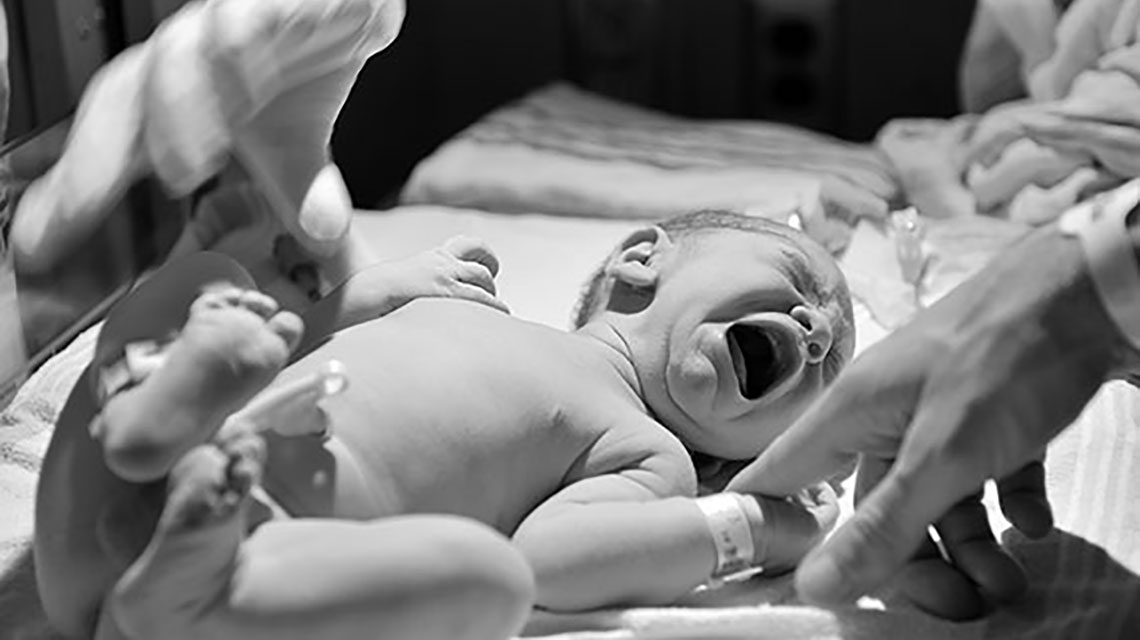 Black and white photo of infant crying in hospital
