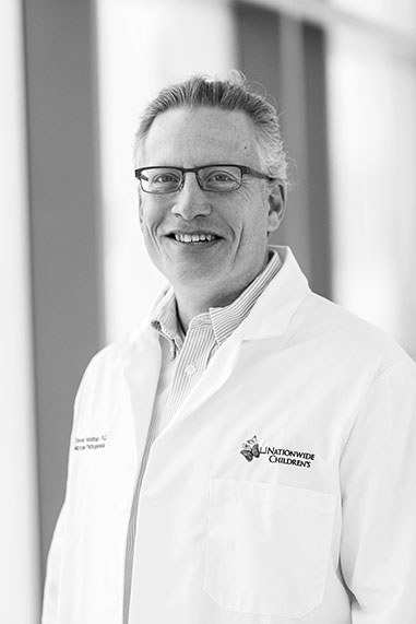 Dr. Steve Goodman, black and white environmental portrait in lab coat