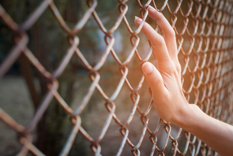 Photo of a hand holding a fence