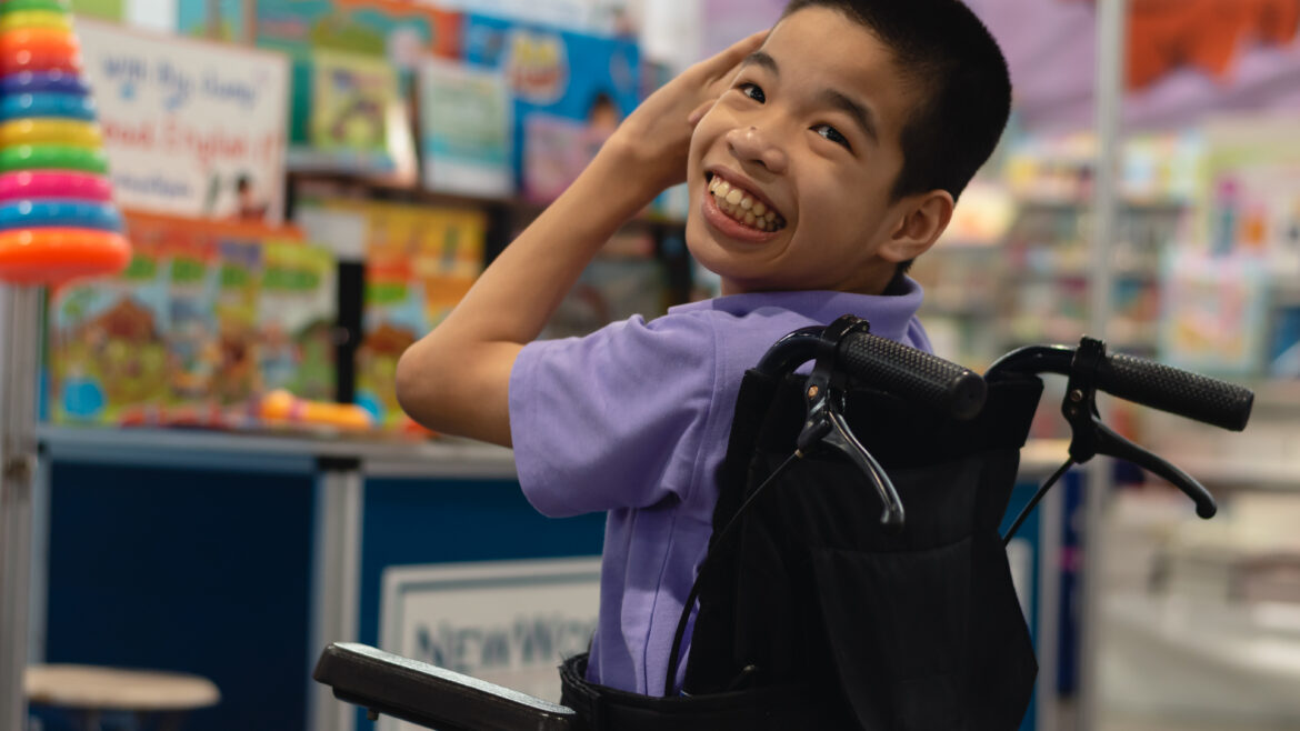Child on a wheel chair looking back smiling at the camera