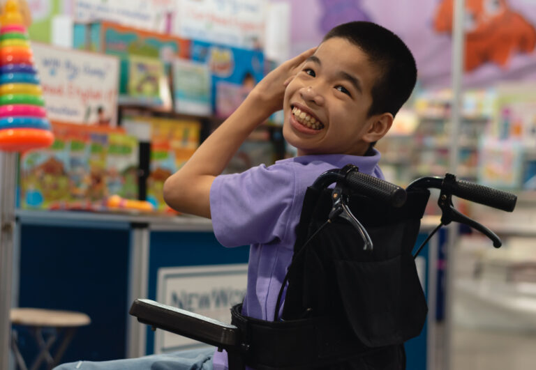 Child on a wheel chair looking back smiling at the camera