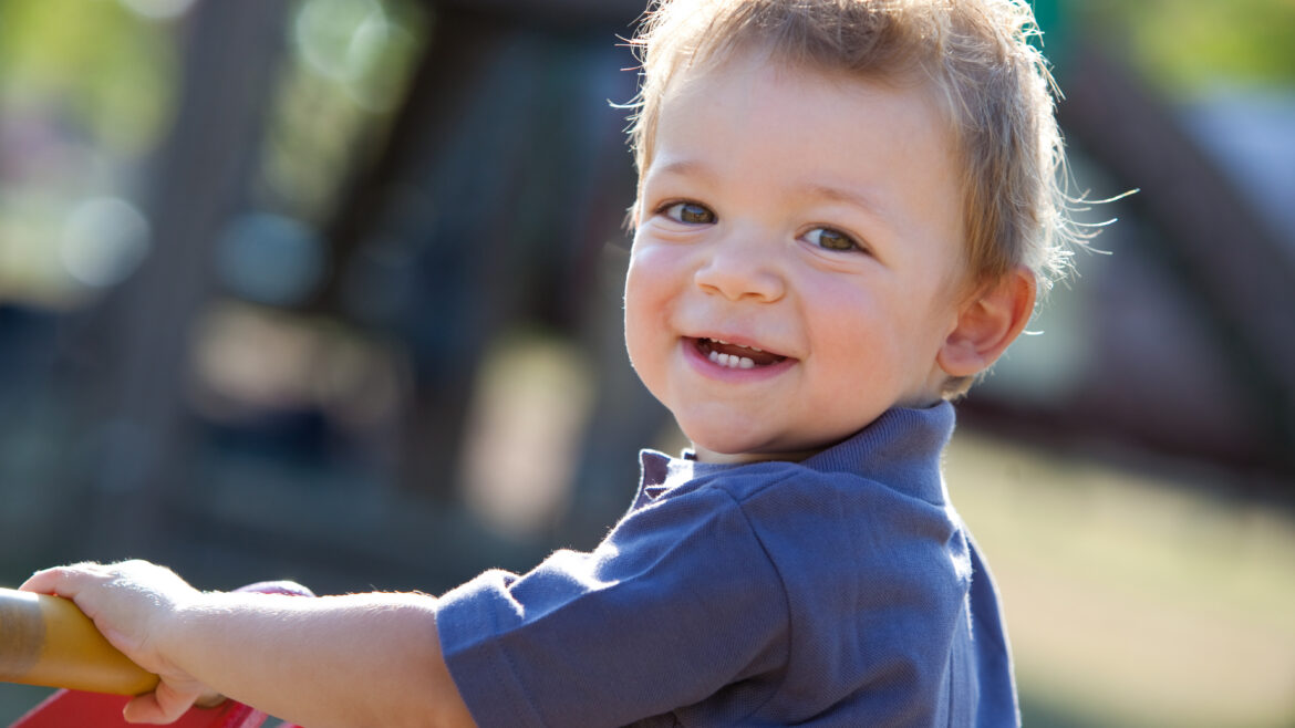 child playing outside smiling at the camera
