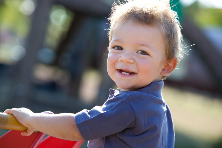 child playing outside smiling at the camera