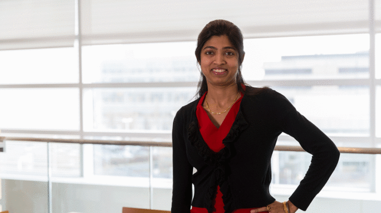 Rajeswari Swaminathan smiling and posing for photo in front of windows