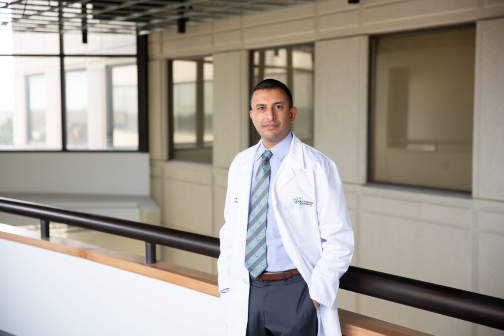 Dr. Anup D. Patel, MD standing in a hallway wearing a white lab coat