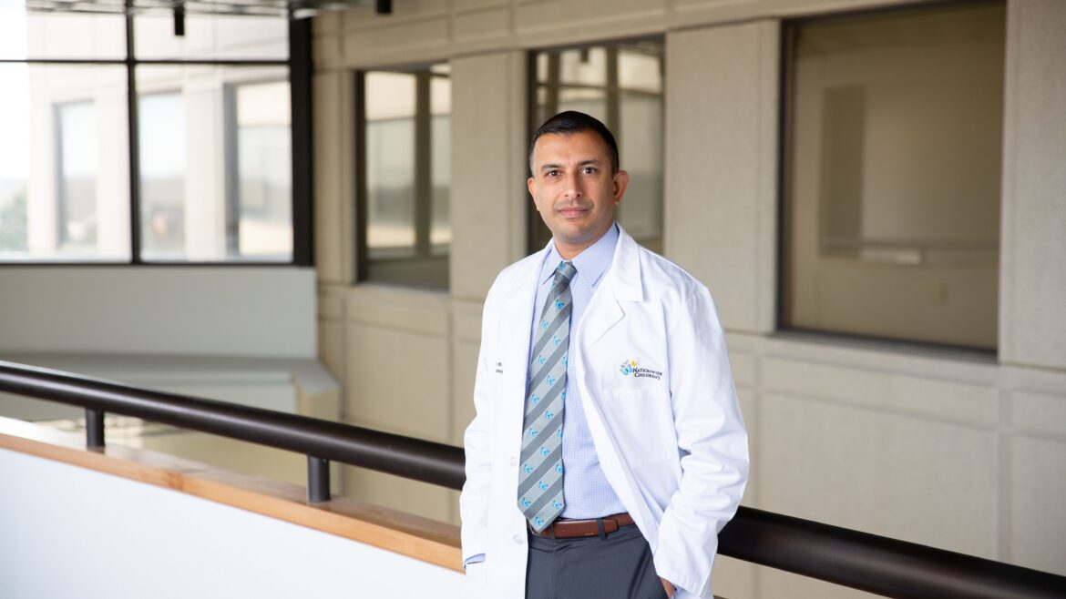 Dr. Anup D. Patel, MD standing in a hallway wearing a white lab coat