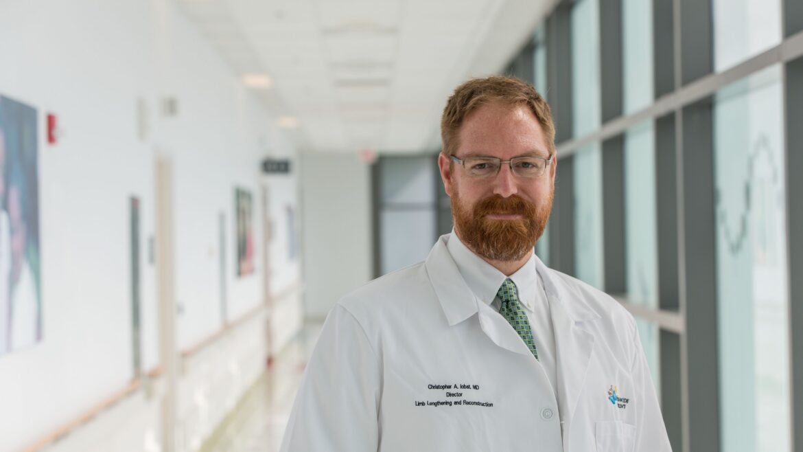 Dr. Christopher A. Iobst, MD, in a white lab coat in a white medical hallway