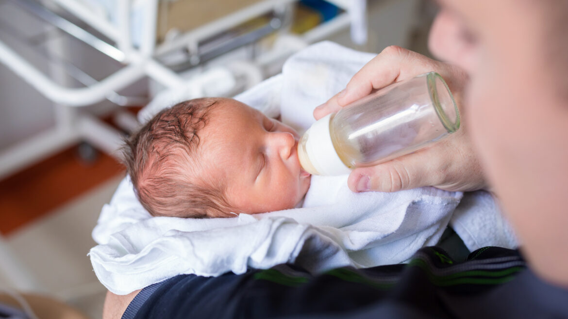 Father feeding his tiny baby boy in the hospital