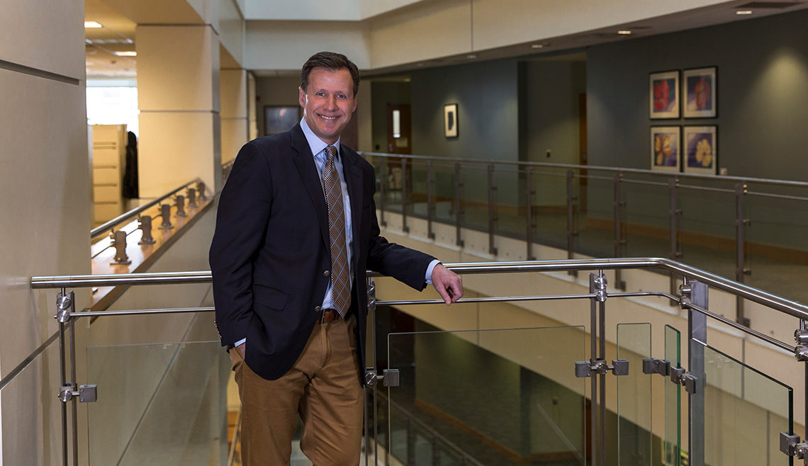 Dr. Dennis Durbin standing next to a railing inside a building