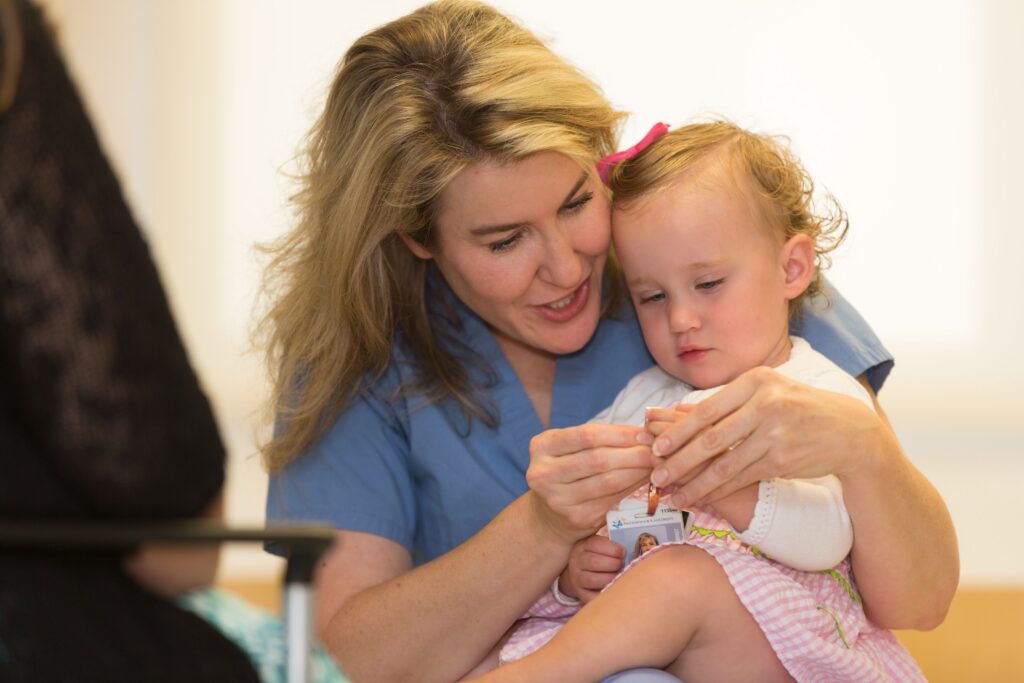 Dr. Maitre engages warmly with a young child, Taryn, helping her with a small medical item.