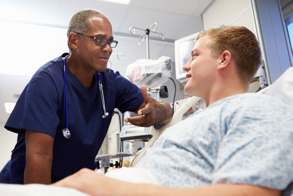 Health care provider talking to male teen patient