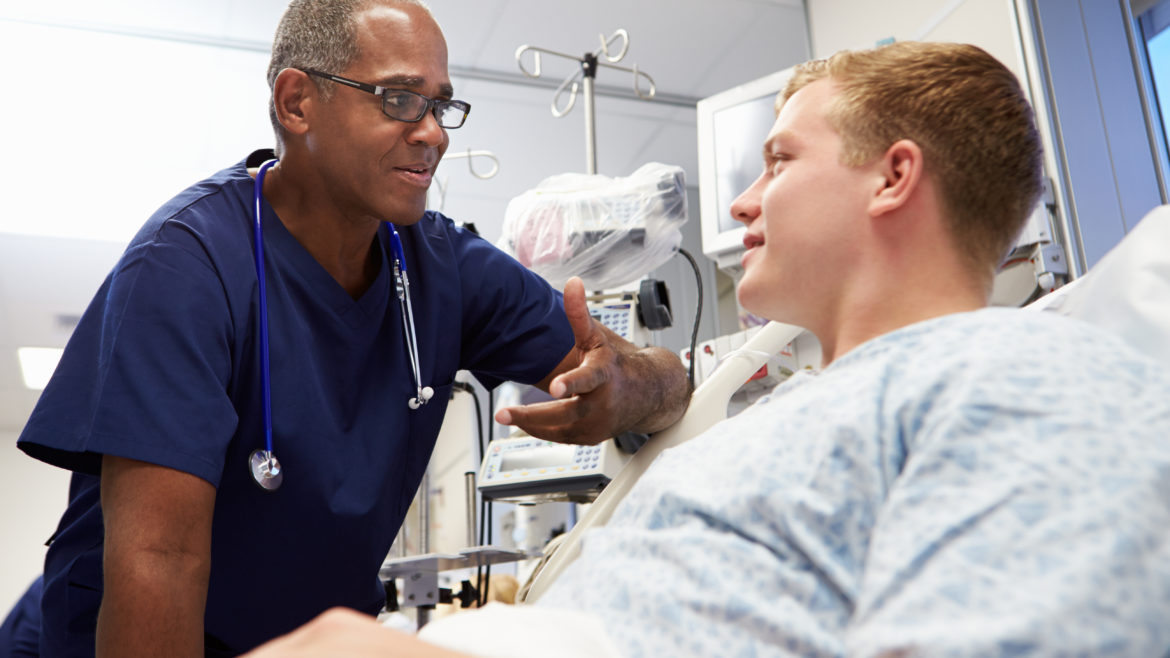Health care provider talking to male teen patient