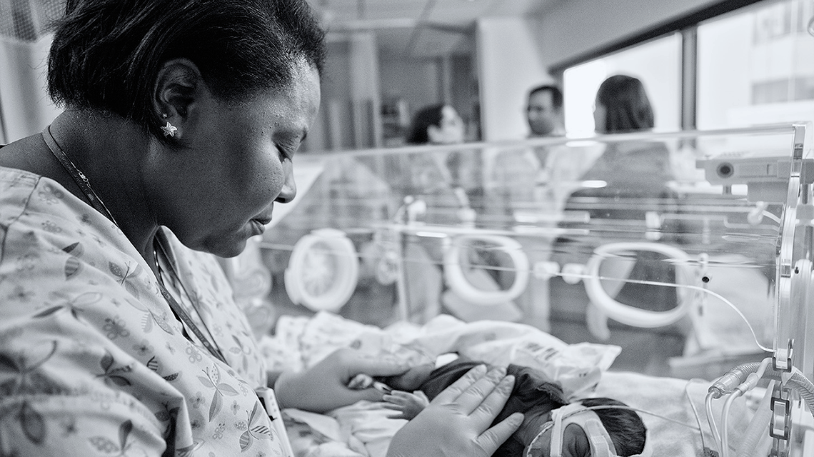 Nurse caring for infant in Neonatal Intensive Care Unit (NICU)