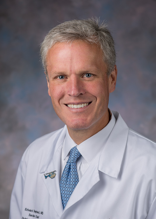 studio portrait of Edward Shepherd, MD. He is wearing a white coat, white shirt and blue tie.