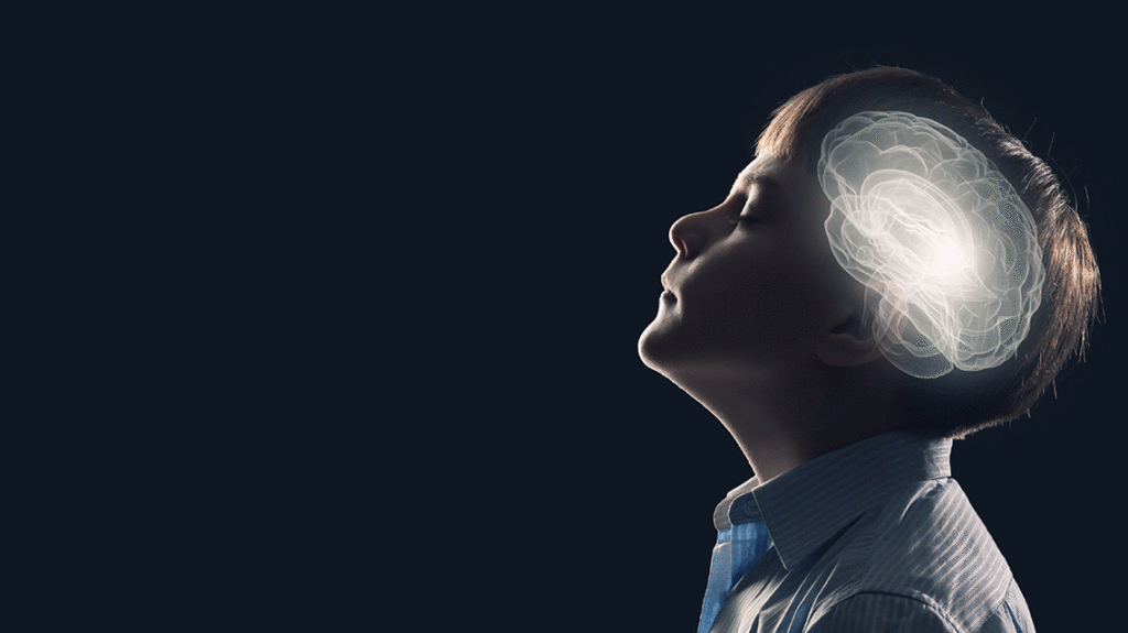 Young boy turned sideways in front of a dark background, with dark lighting and an illustration of his brain appearing in front of the side of his head