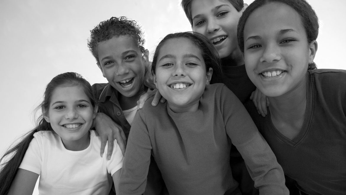 Black and white image of five smiling kids/adolescents