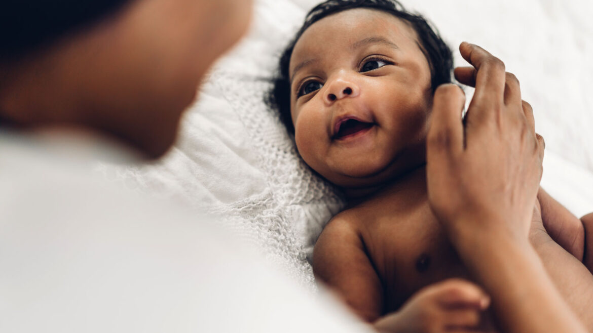Black baby smiling up at his mother