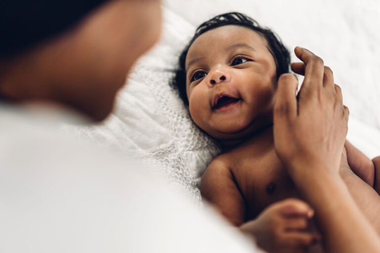 Black baby smiling up at his mother