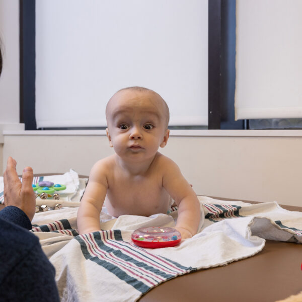 Baby on doctor's office exam table doing tummy time and holding his head high.