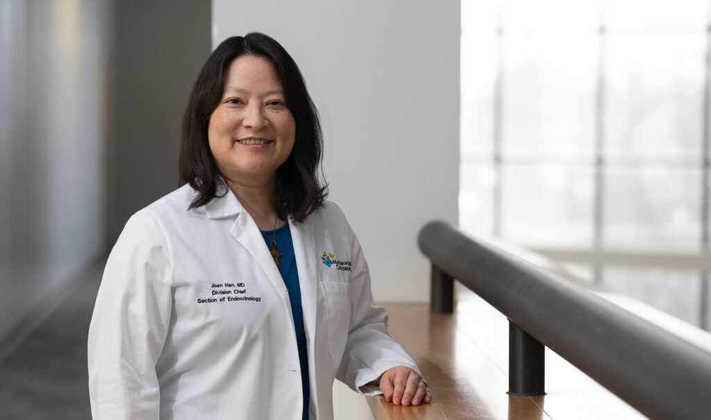 Dr. Joan Han standing in a white coat in a hospital setting