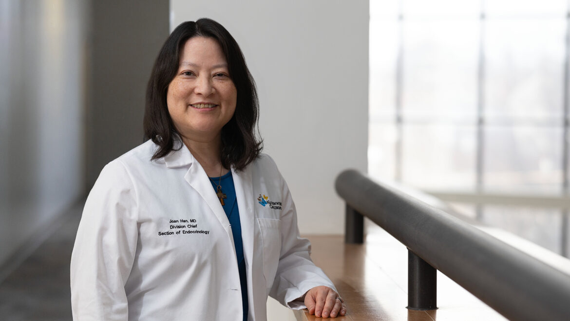 Dr. Joan Han standing in a white coat in a hospital setting