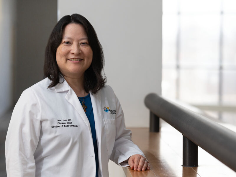 Dr. Joan Han standing in a white coat in a hospital setting