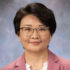 Studio portrait of Yan Hu, PhD, wearing a cream shirt and pink blazer