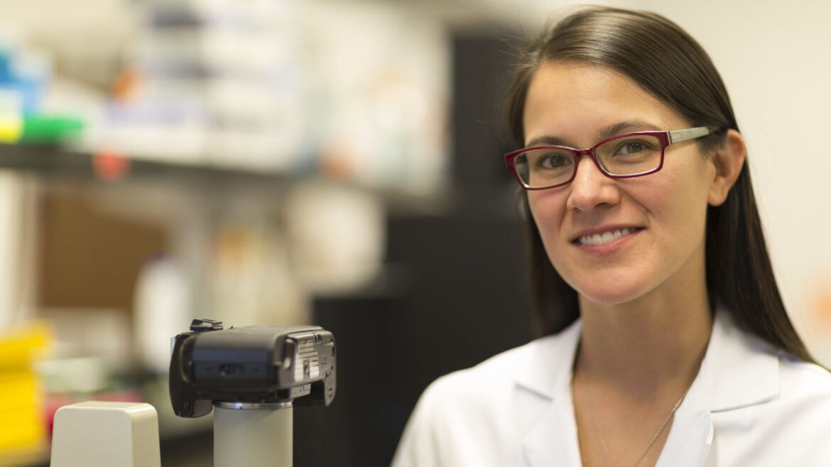Photo of Christina Ching, MD, wearing a white lab coat, smiling at the camera in a lab.