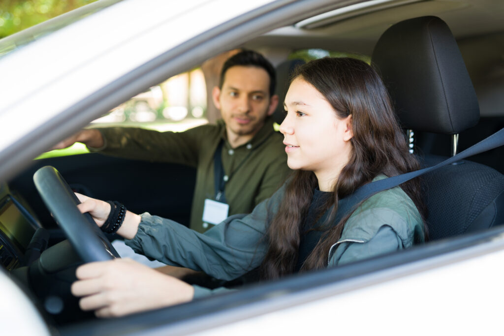 Caucasian adolescent girl paying attention to the road and listening to her instructor. Teenage girl driving during her test to get a driver's license