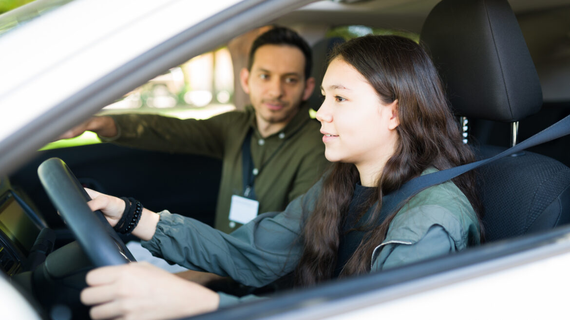 Caucasian adolescent girl paying attention to the road and listening to her instructor. Teenage girl driving during her test to get a driver's license