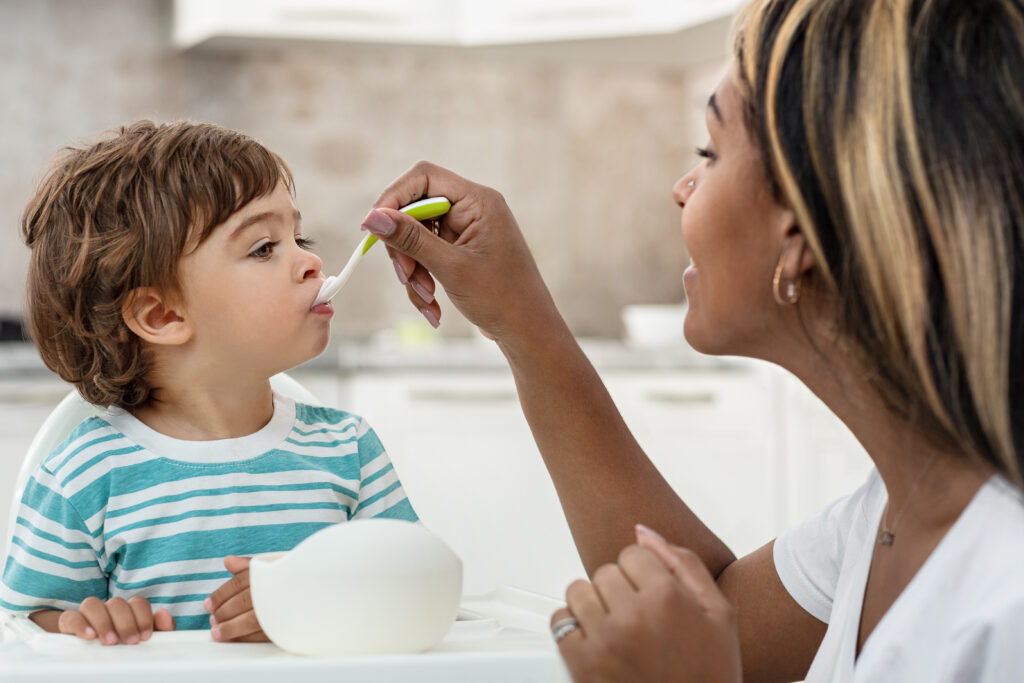 Woman is spoon feeding a toddler