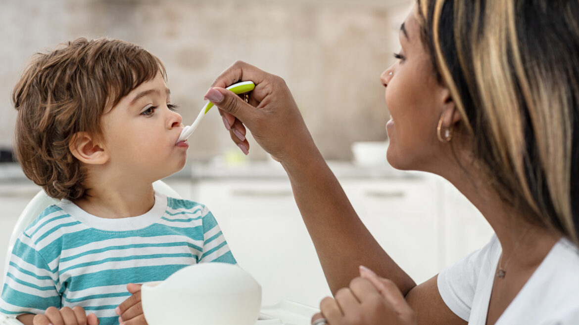 Woman is spoon feeding a toddler