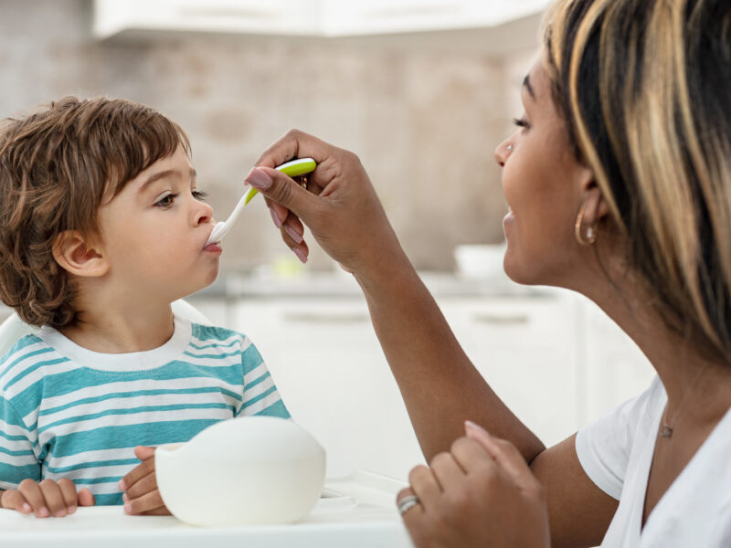 Woman is spoon feeding a toddler