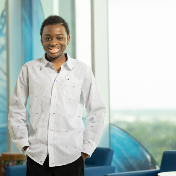 King Robinson - a young patient at Nationwide Children's - smiling and standing next to a window inside the hospital