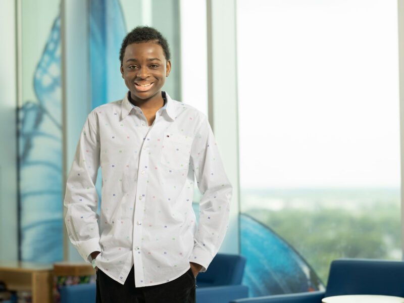 King Robinson - a young patient at Nationwide Children's - smiling and standing next to a window inside the hospital